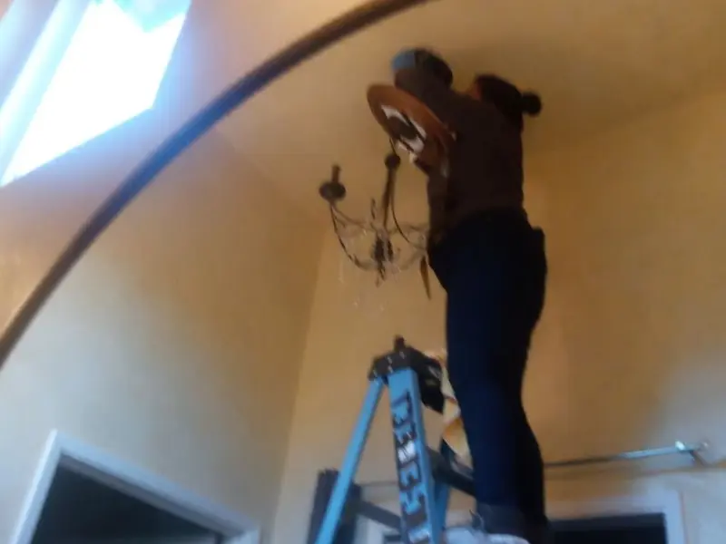 Electrician installing a chandelier in a Barrington residence